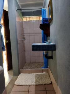 a bathroom with a shower with a blue sink at Hostal Xilotl in San José del Sur