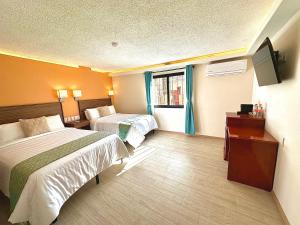 a hotel room with two beds and a television at Suites del Jardín Principal in Guanajuato