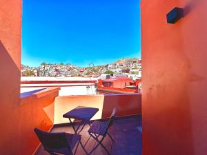 a table and chairs on a balcony with a view at Suites del Jardín Principal in Guanajuato