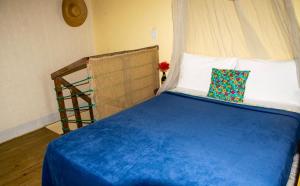 Mini Chalés Madeira Beach في أوباتوبا: غرفة نوم بسرير وملاءات زرقاء وسلم