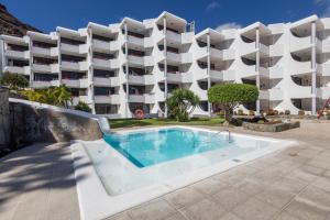 una piscina frente a un gran edificio de apartamentos en Lightbooking Playa Cura Mogan, en Playa del Cura