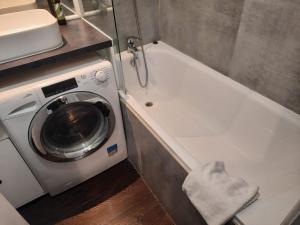 a washing machine sitting next to a white bath tub at Grand appartement avec balcon - Proche Parc des Expo - Parking Privée in Issy-les-Moulineaux