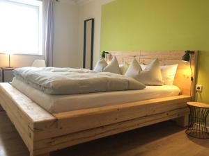 1 dormitorio con cama de madera y almohadas blancas en Wiesen-Hof, 