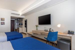 Cette chambre comprend un lit, un bureau et une télévision. dans l'établissement Premium Inn Mombasa City, à Mombasa