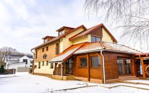 a wooden house with snow on the ground at Troika Penzión in Pavčina Lehota
