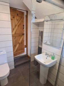 a bathroom with a sink and a toilet and a door at The Willow (Alton Towers, Animals, Peak District) in Denstone