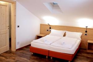 a bedroom with a large white bed with two pillows at Ski Lodge Pampeago in Tesero