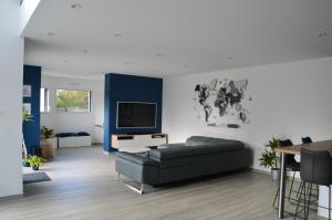 ein Wohnzimmer mit einem Sofa und einem TV in der Unterkunft Villa d'architecte tout près d'Honfleur - SPA in Équemauville