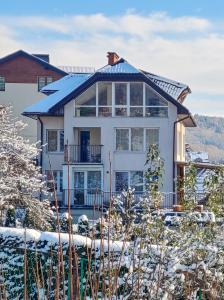 a large white house with snow on the ground at Apartament u Tomka Lux in Ustrzyki Dolne