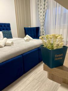 een blauw bed met een blauwe bank en een potplant bij Q Elegance Palas Mall in Iaşi