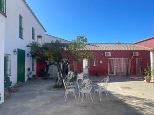 um grupo de cadeiras e mesas em frente a um edifício vermelho em Casa Muriana em Alanís