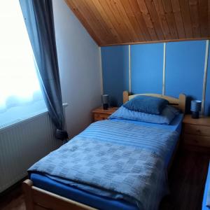 a bedroom with a bed with a blue comforter and a window at Agroturystyka u Rysia in Kamienna