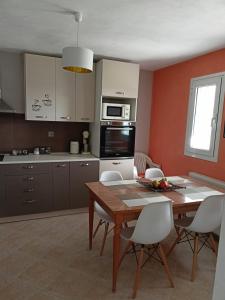 a kitchen with a wooden table and white chairs at Little garden house in Krinítsa