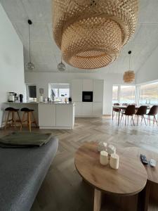 a living room with a table and a large chandelier at Brand New Waterfront-Apartment in Hvalvík