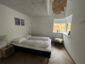a bedroom with a bed in a room with a window at Brand New Waterfront-Apartment in Hvalvík