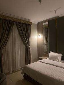 a bedroom with a bed and a large window at Ajwa Suites for Furnished Units in Jeddah