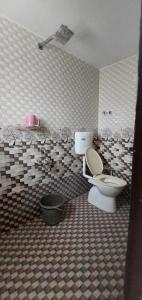 a bathroom with a toilet and a tiled wall at OYO Flagship Hotel Royal Galaxy in Nagpur