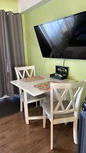 mesa blanca con 2 sillas y TV en la pared en Bonheur partagé, en Lévis
