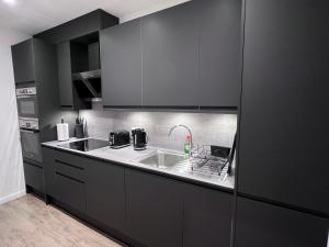 a kitchen with black cabinets and a sink at Flat in central London with large patio in London