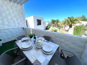 a table with plates and wine bottles on a balcony at Apartamento Bungamerica 2 bedrooms Costa Adeje in Playa de las Americas