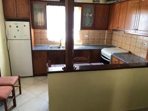 a kitchen with wooden cabinets and a white refrigerator at Quality home in Sarandë