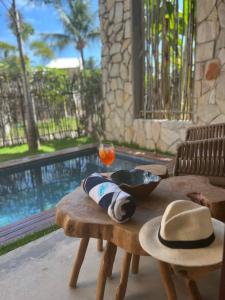 - une table en bois avec un chapeau et une boisson dans l'établissement Casa de luxo na Praia do Patacho - Cond. Azulu, Casa 04, à Porto de Pedras