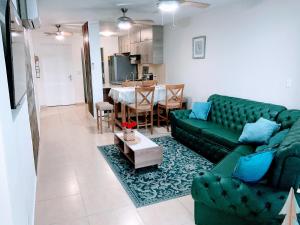 パナマシティにあるPunta Pacífica Oceanfront apartmentのリビングルーム(緑のソファ、テーブル付)