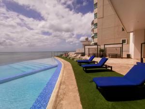 uma piscina com espreguiçadeiras azuis ao lado de um edifício em Punta Pacífica Oceanfront apartment na Cidade do Panamá