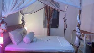 ein Schlafzimmer mit einem Himmelbett mit weißer Bettwäsche und Kissen in der Unterkunft African Angel House B&B in Stone Town