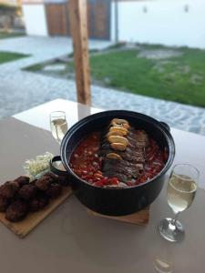 a pan of food on a table with wine glasses at Villa Apartments B&D in Ohrid