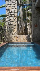 - une piscine en face d'un bâtiment en pierre dans l'établissement Casa de luxo na Praia do Patacho - Cond. Azulu, Casa 04, à Porto de Pedras