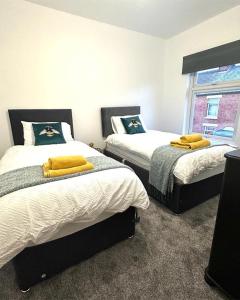 a bedroom with two beds with yellow towels on them at No.24 in Sandbach