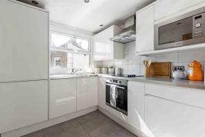 a white kitchen with a sink and a stove at Wandsworth house in London