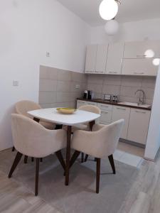 cocina con mesa blanca y sillas en JAGODINA apartman en Jagodina