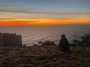 Hermoso Depto nuevo, Reñaca ConCon vista al mar في كونكون: شخص يجلس على الشاطئ عند غروب الشمس