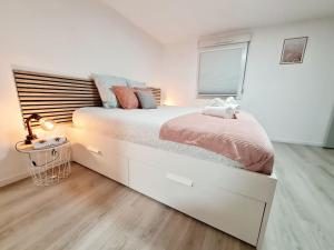 een witte slaapkamer met een groot bed met roze lakens bij Meublé Flora pour voyageur pro - Centre, calme - Wi-Fi in Haguenau