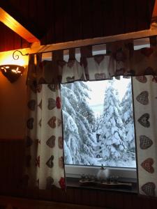 una ventana con un árbol de Navidad cubierto de nieve en Apartma Tisa, en Zreče