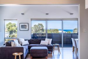 uma sala de estar com um sofá azul e janelas em Hazards Escape - the Top Shack & the Short Stack em Coles Bay
