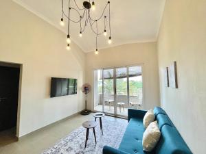 a living room with a blue couch and a chandelier at Pebble Bay Garden View F3 in Grand-Baie