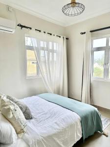 a white bedroom with a bed and a window at Pebble Bay Garden View F3 in Grand-Baie