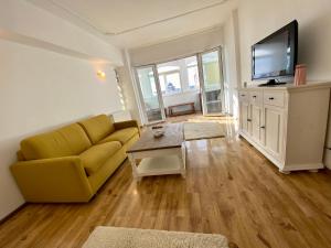 a living room with a yellow couch and a tv at Downtown Apartment in Craiova