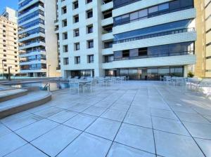 une terrasse en face d'un bâtiment avec des tables et des chaises dans l'établissement Apartamento Beira Mar em Recife, à Récife