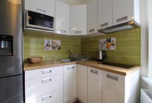 a kitchen with white cabinets and a stainless steel refrigerator at Great Amber Apartment in Liepāja