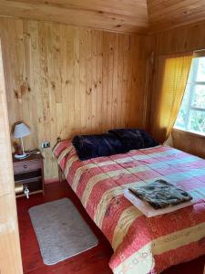ein Schlafzimmer mit einem Bett mit einer Holzwand in der Unterkunft Cabaña 4 personas en Calen Rural, Chiloé in Dalcahue