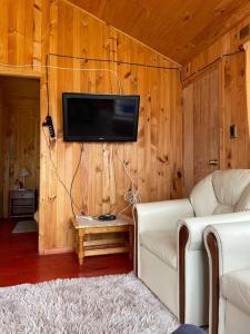 ein Wohnzimmer mit einem Sofa und einem TV an der Wand in der Unterkunft Cabaña 4 personas en Calen Rural, Chiloé in Dalcahue