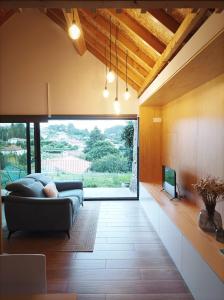 a living room with a couch and a large window at Casas das Japoneiras in Paredes de Coura
