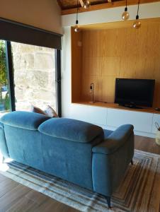 a blue couch in a living room with a tv at Casas das Japoneiras in Paredes de Coura