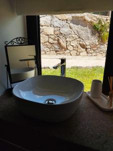 um lavatório branco numa casa de banho com uma janela em Casas das Japoneiras em Paredes de Coura