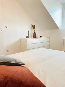 a white bedroom with a bed and a dresser at Appartement Duplex Cosy in Le Havre