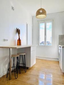 a kitchen with a table and stools and a window at Appartement Duplex Cosy in Le Havre